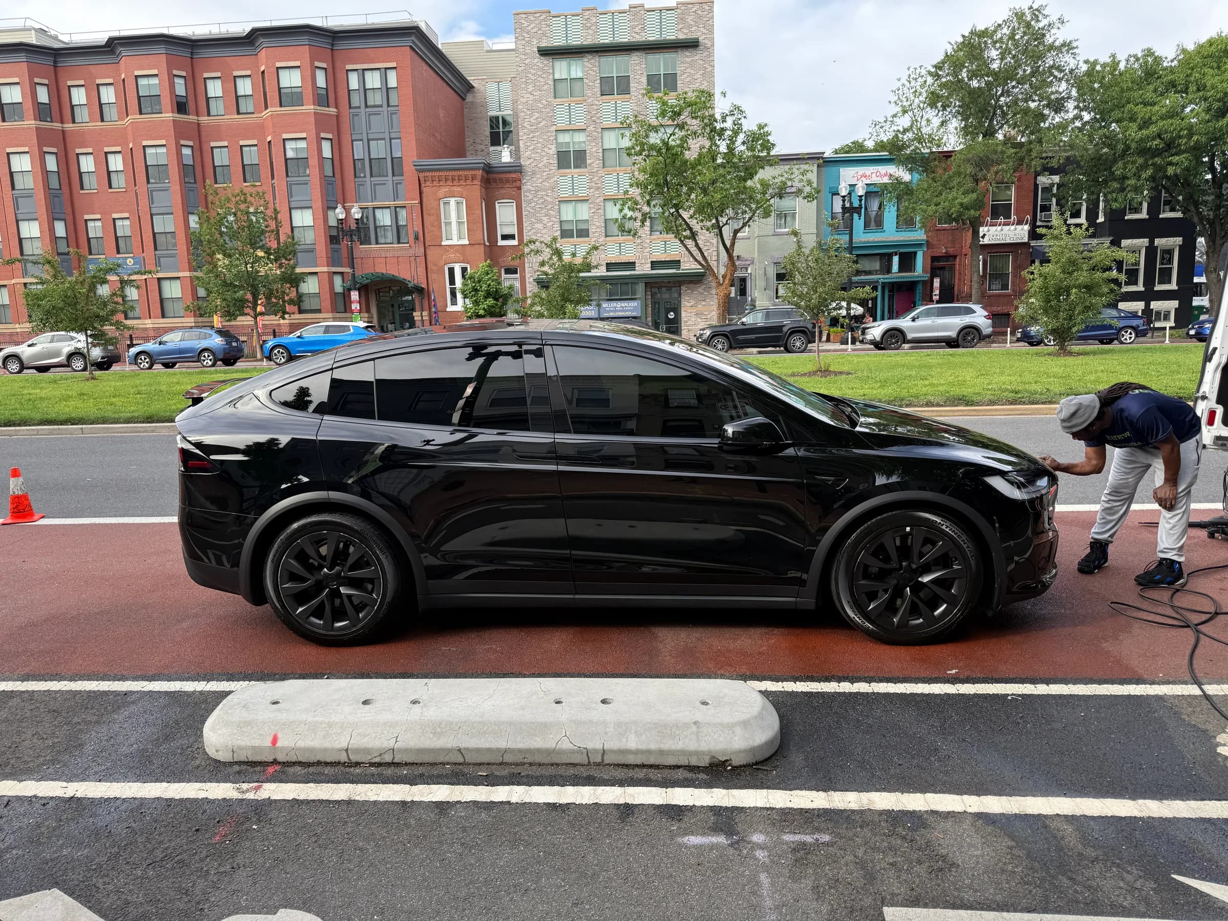 Black Tesla Model X side profile being detailed on a city street Black Tesla Model X side profile being detailed on a city street
